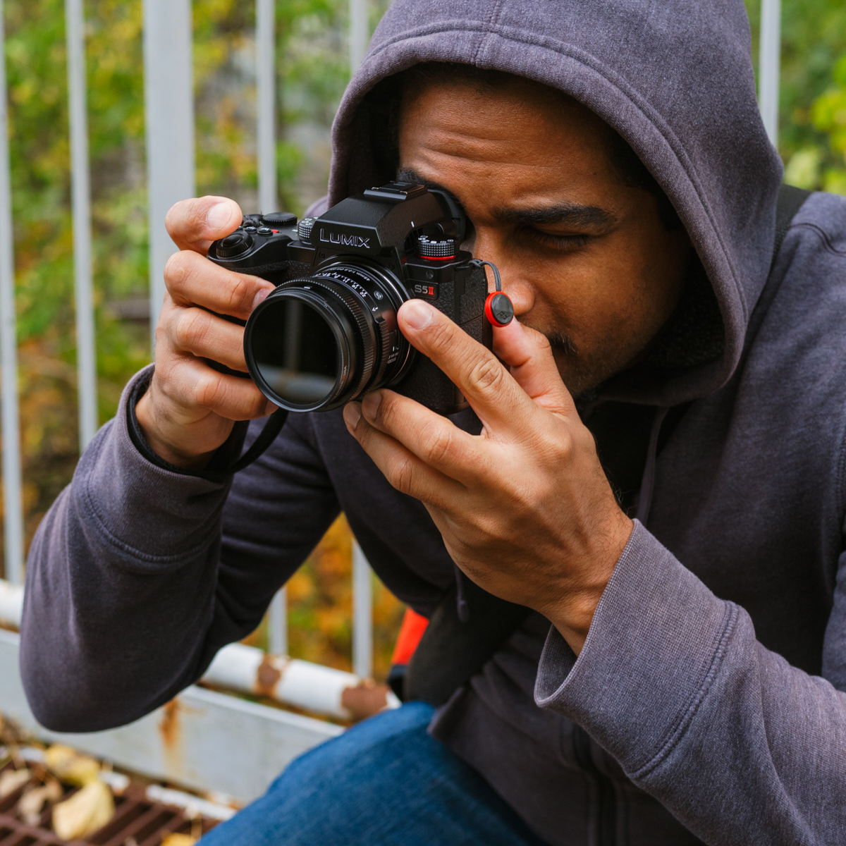 Antonio Grande looking through a black camera. He is wearing a grey hoodie sweater.